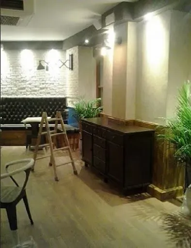 Salón interior moderno con escalera, armario oscuro, plantas y pared decorativa blanca estampada.